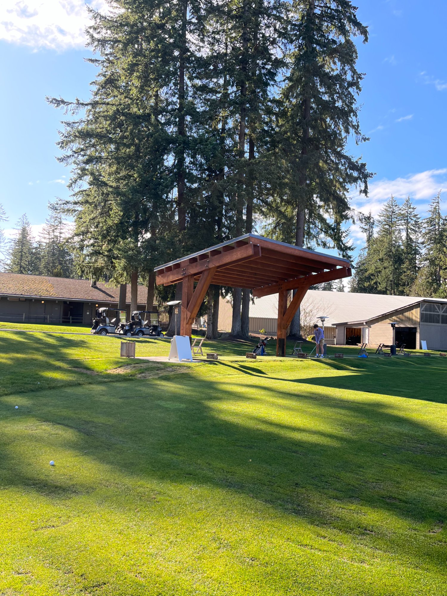 TimberShield V-leg residential golf practice cover at golden hour — TS-12 with glass roof in luxury backyard